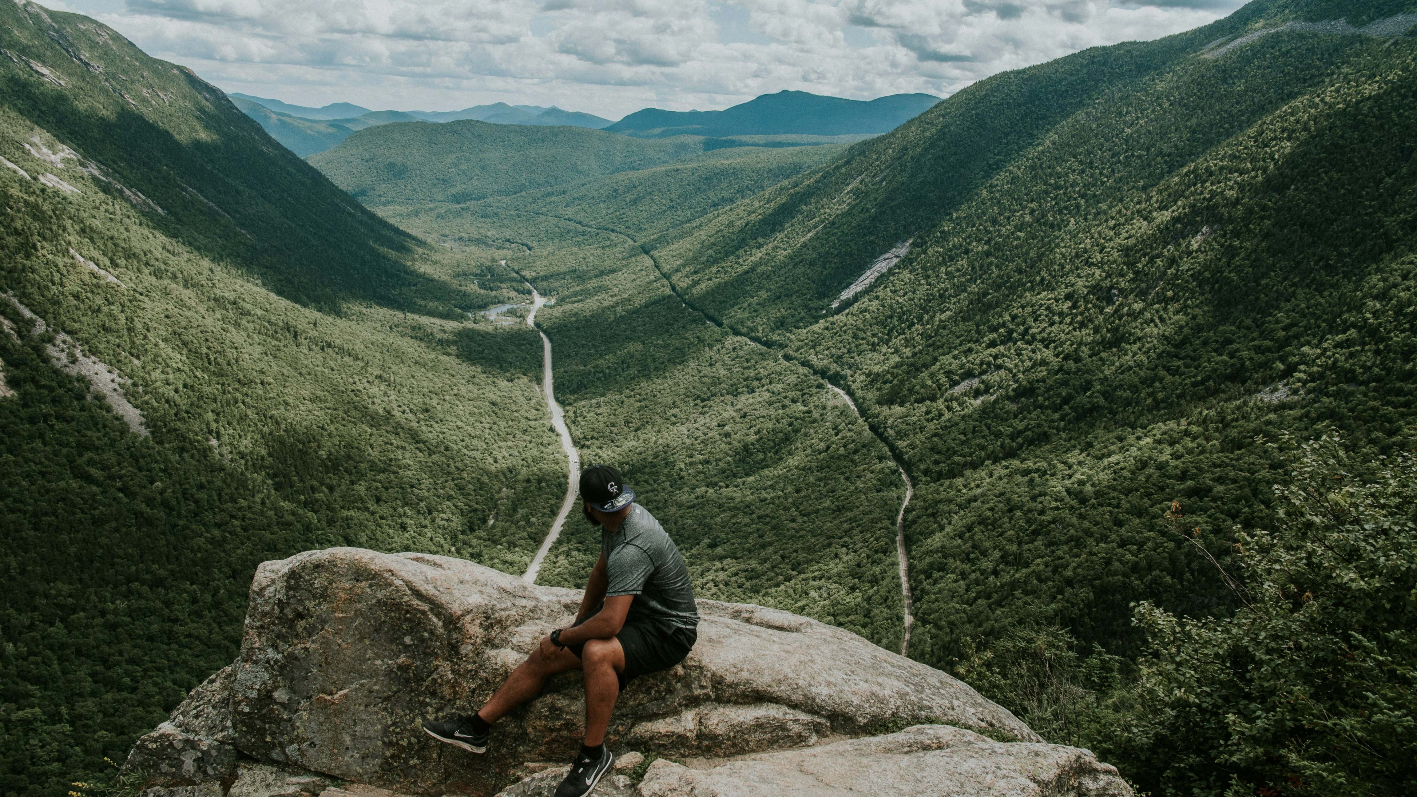 man sitting on rock looking at mountain